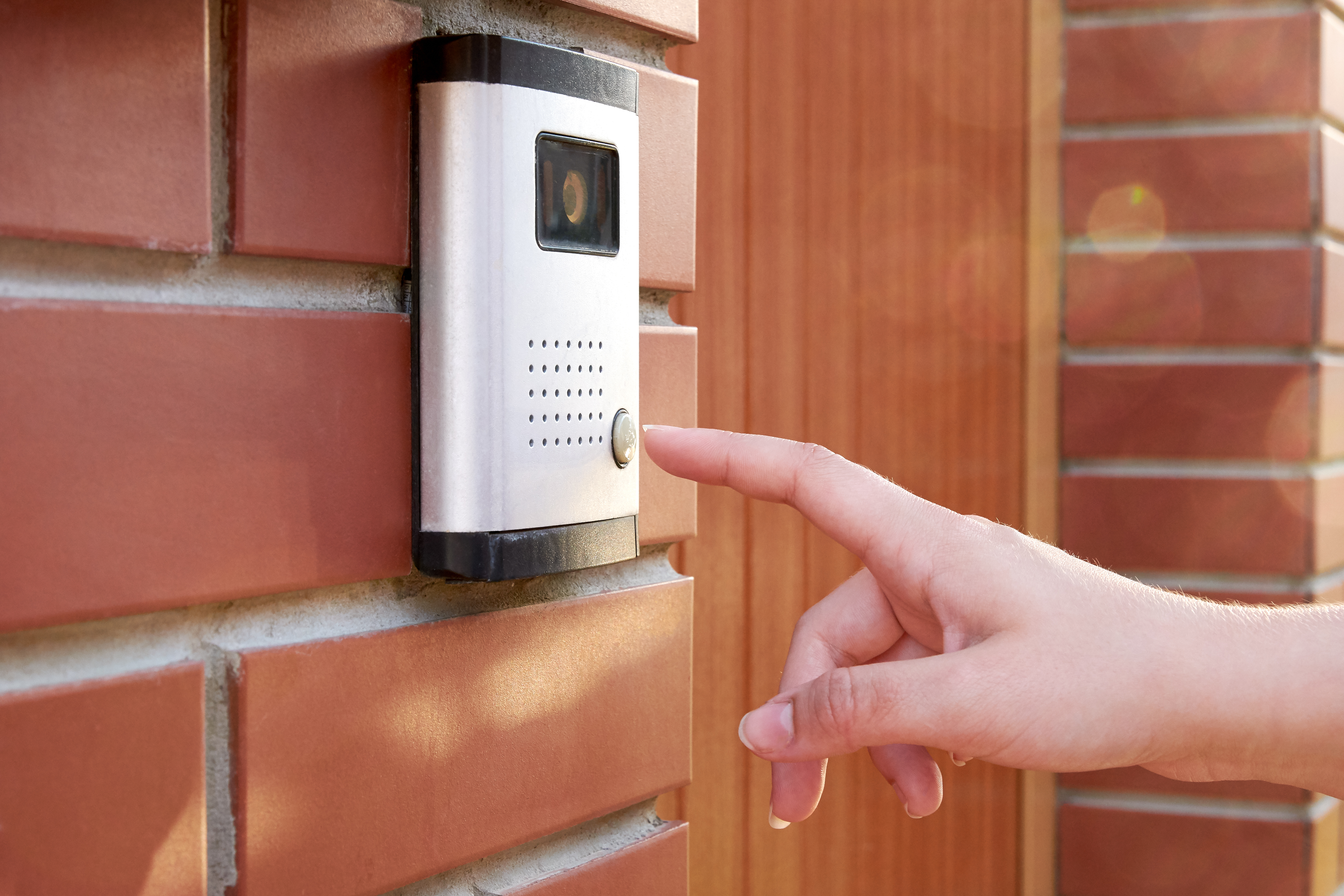 person pressing a camera doorbell